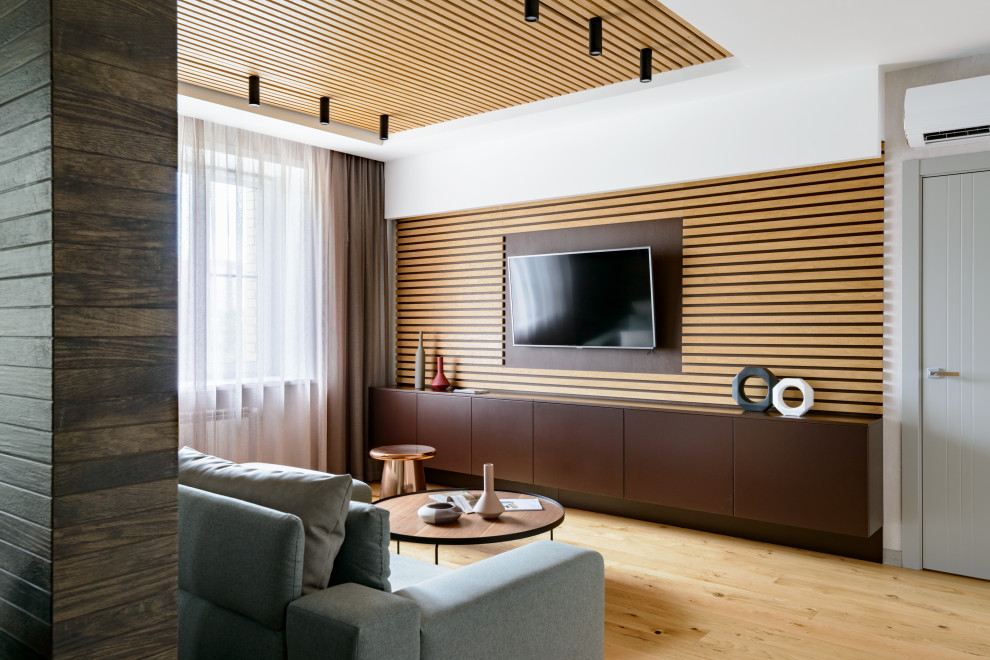 Стильный дизайн: парадная, открытая гостиная комната в современном стиле с белыми стенами, телевизором на стене и коричневым полом - последний тренд