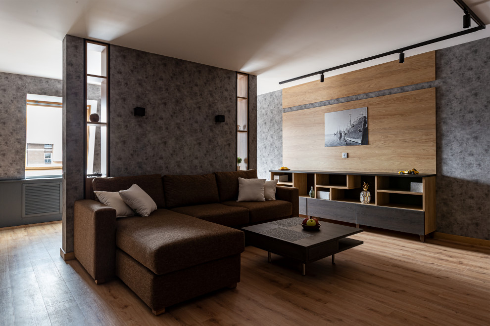 Свежая идея для дизайна: большая гостиная комната в современном стиле с серыми стенами, полом из ламината, коричневым полом и обоями на стенах - отличное фото интерьера