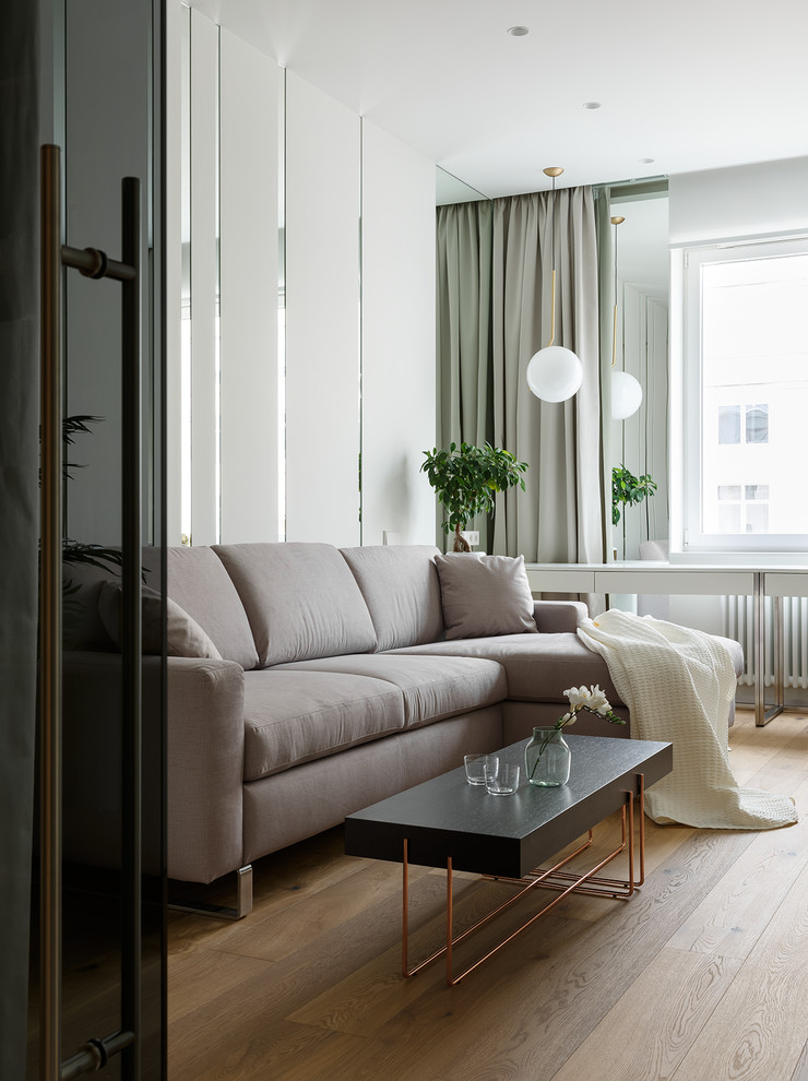 Свежая идея для дизайна: гостиная комната среднего размера в современном стиле с белыми стенами, паркетным полом среднего тона, телевизором на стене и коричневым полом - отличное фото интерьера