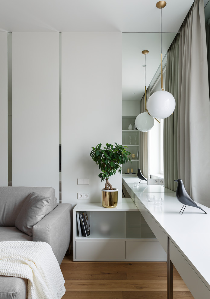 Свежая идея для дизайна: гостиная комната среднего размера в современном стиле с белыми стенами, паркетным полом среднего тона, телевизором на стене и коричневым полом - отличное фото интерьера