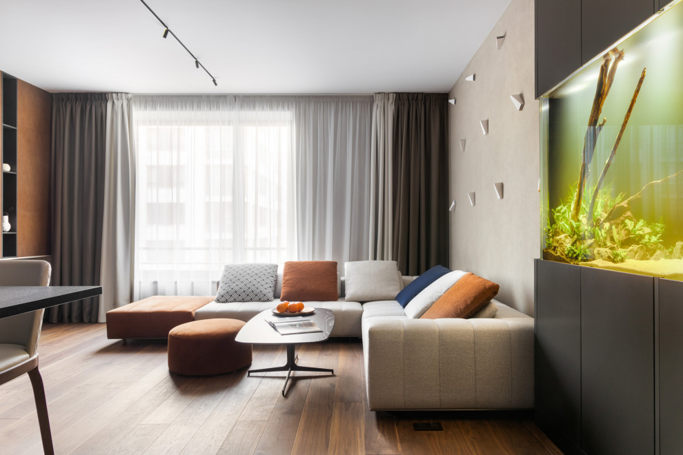 Стильный дизайн: большая открытая гостиная комната в современном стиле с бежевыми стенами, паркетным полом среднего тона, телевизором на стене и коричневым полом - последний тренд