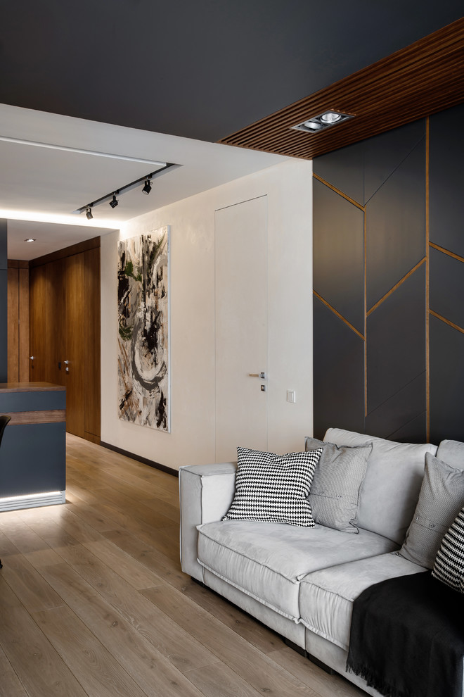 Ejemplo de salón actual de tamaño medio con paredes blancas, suelo de madera en tonos medios y televisor colgado en la pared