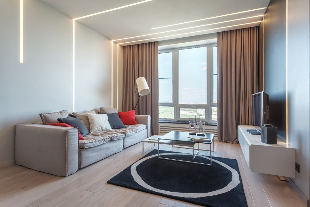 Ejemplo de salón contemporáneo con paredes blancas, suelo de madera clara, televisor independiente y suelo beige