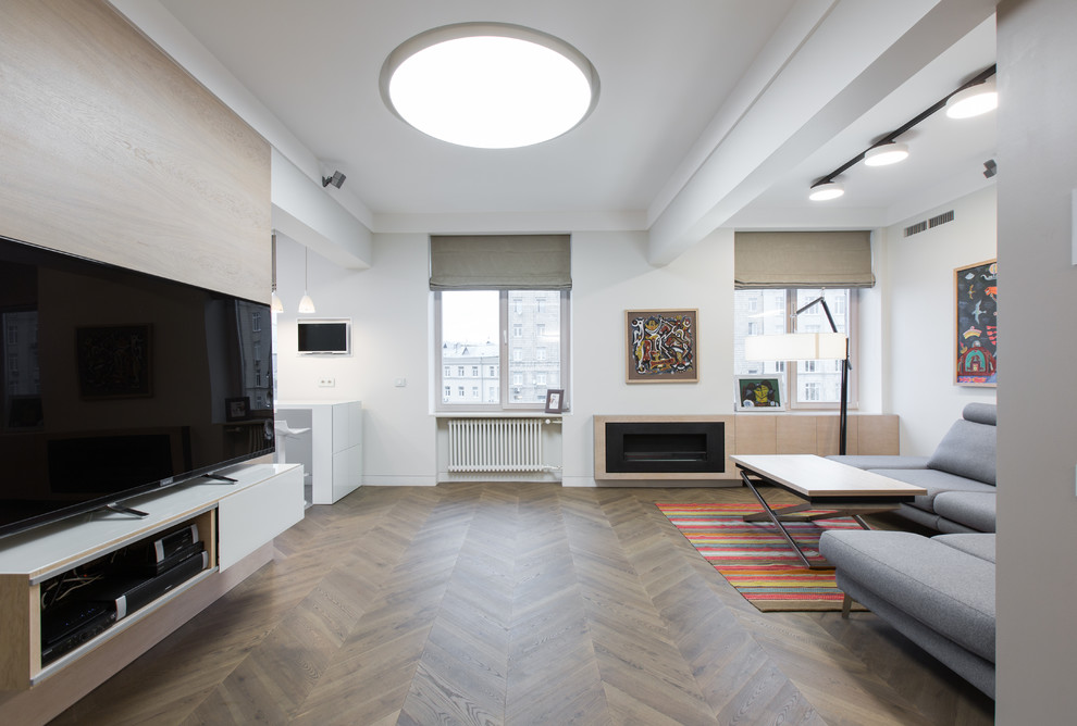 Aménagement d'un grand salon contemporain ouvert avec un mur blanc, un sol en bois brun, cheminée suspendue, un manteau de cheminée en bois et un téléviseur indépendant.