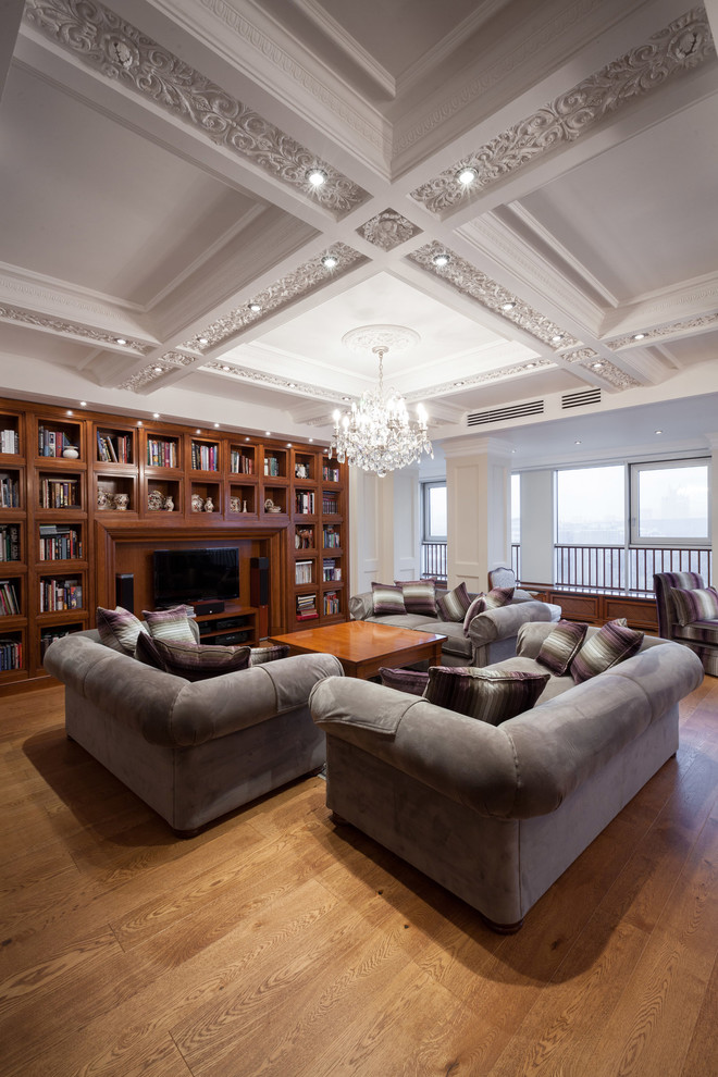 Modelo de biblioteca en casa abierta clásica grande sin chimenea con paredes beige, suelo de madera pintada y pared multimedia
