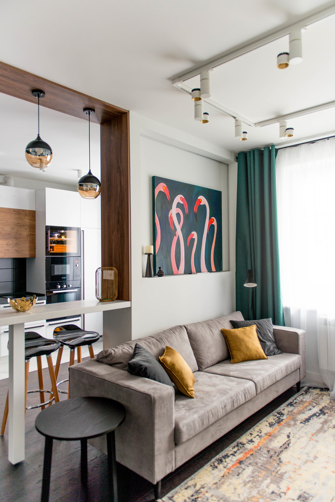 Пример оригинального дизайна: маленькая открытая, объединенная гостиная комната в современном стиле с белыми стенами, темным паркетным полом, телевизором на стене и коричневым полом для на участке и в саду