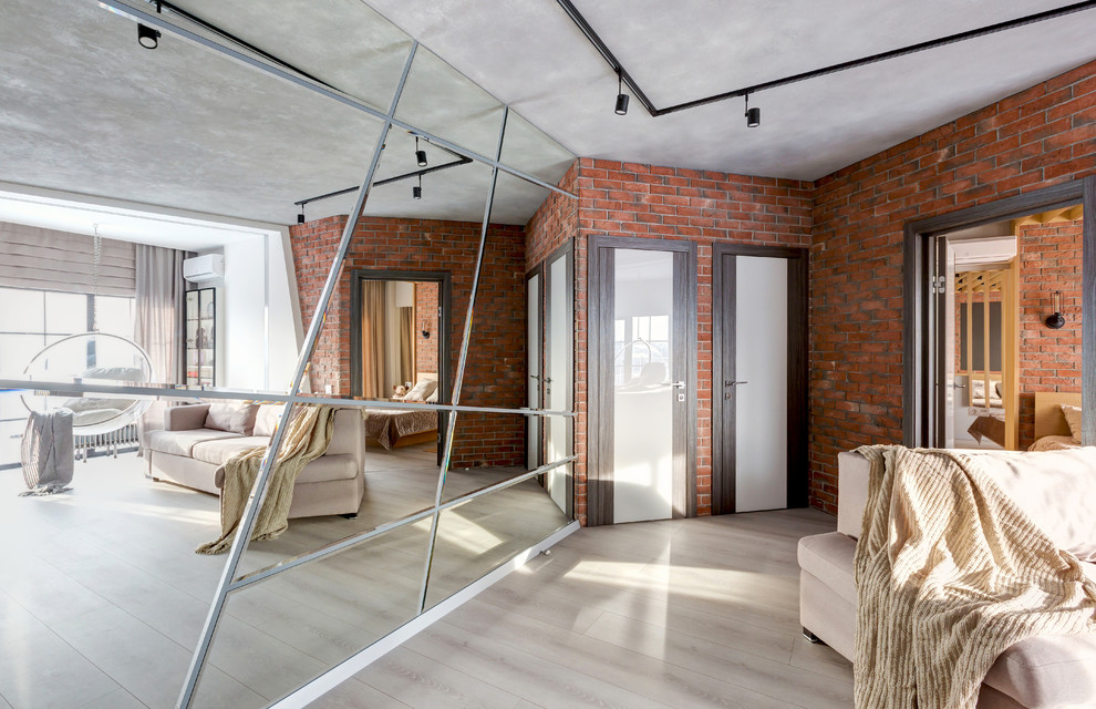 Modelo de salón para visitas tipo loft urbano de tamaño medio sin chimenea con paredes blancas, suelo laminado, televisor colgado en la pared y suelo gris