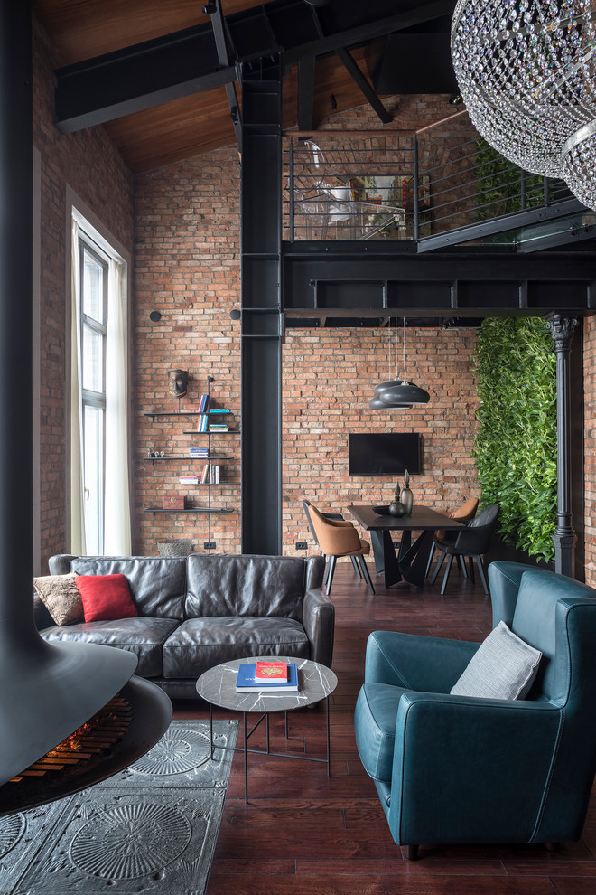 Foto de salón abierto urbano con paredes marrones, suelo de madera oscura, chimeneas suspendidas, marco de chimenea de metal y suelo marrón