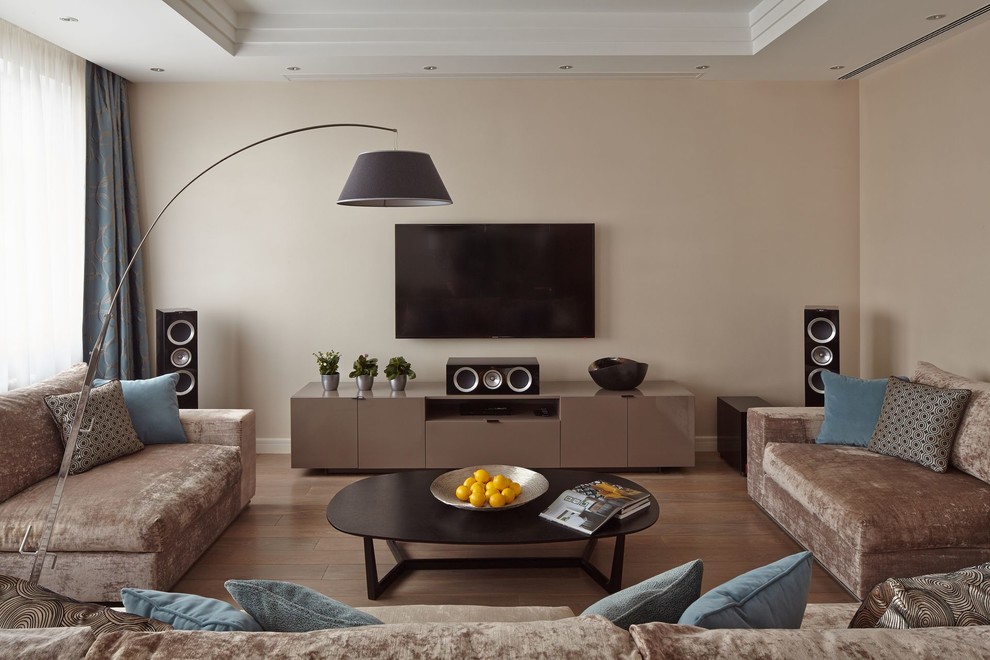 Свежая идея для дизайна: открытая гостиная комната в современном стиле с бежевыми стенами, паркетным полом среднего тона, телевизором на стене и коричневым полом - отличное фото интерьера