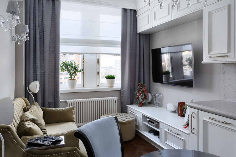 Imagen de sala de estar abierta clásica con paredes blancas, televisor colgado en la pared, suelo marrón y suelo de madera en tonos medios