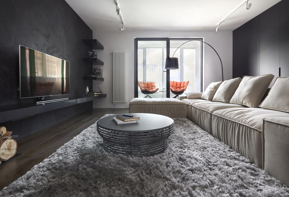 Esempio di un grande soggiorno design chiuso con pareti nere, pavimento in legno massello medio, TV a parete e pavimento marrone