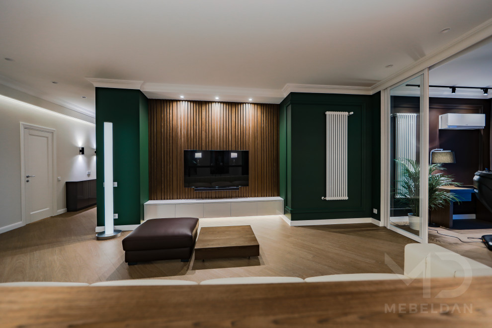 Стильный дизайн: большая гостиная комната в современном стиле с белыми стенами, полом из винила, телевизором на стене, коричневым полом и панелями на части стены - последний тренд