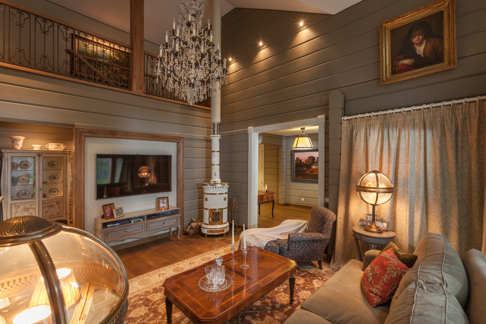Immagine di un soggiorno classico con sala formale, pareti grigie, pavimento in legno massello medio, stufa a legna e TV a parete