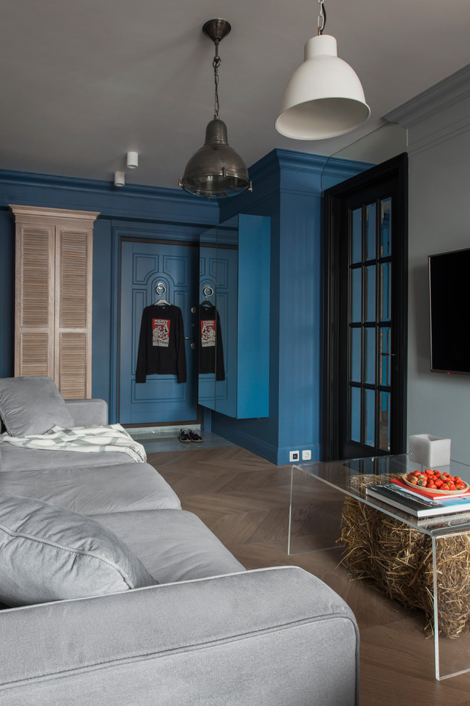 На фото: объединенная гостиная комната в современном стиле с синими стенами, телевизором на стене и светлым паркетным полом