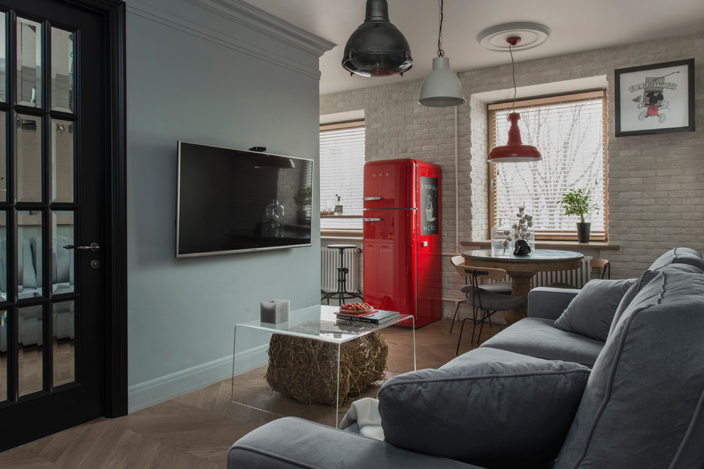 Foto de salón para visitas abierto contemporáneo con paredes grises, suelo de madera en tonos medios y televisor colgado en la pared
