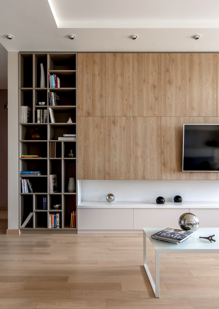 Immagine di un soggiorno minimal di medie dimensioni e chiuso con libreria, pareti beige, pavimento in legno massello medio e TV a parete