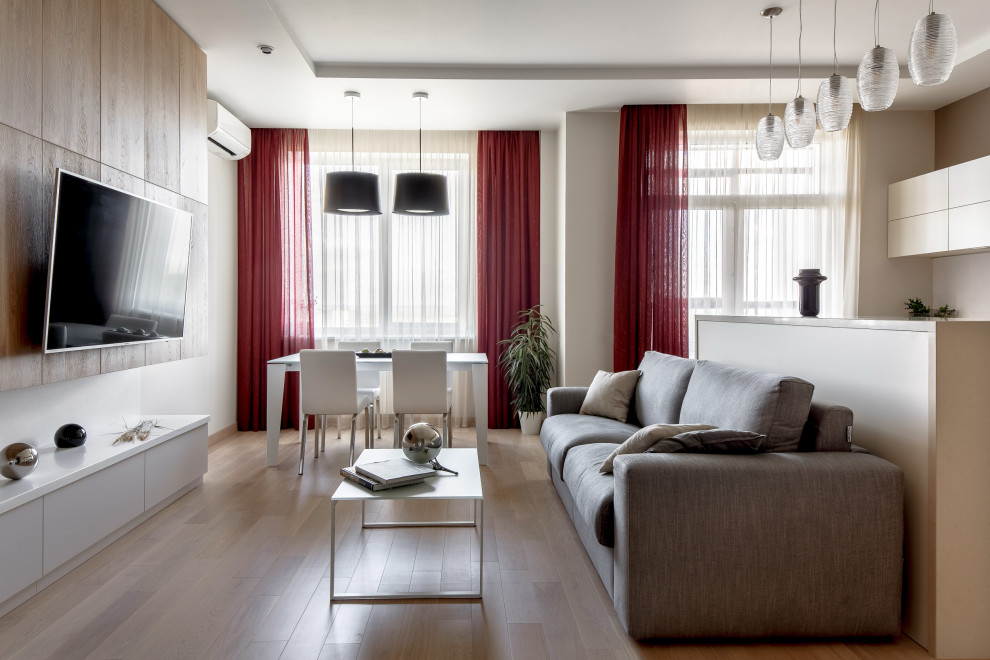 Mittelgroßes, Offenes Modernes Wohnzimmer mit beiger Wandfarbe, braunem Holzboden, TV-Wand, braunem Boden und eingelassener Decke in Sonstige