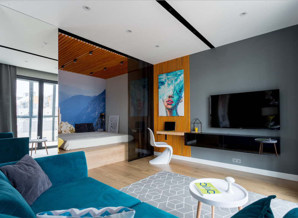 Foto på ett litet funkis vardagsrum, med grå väggar, mellanmörkt trägolv, en väggmonterad TV och brunt golv