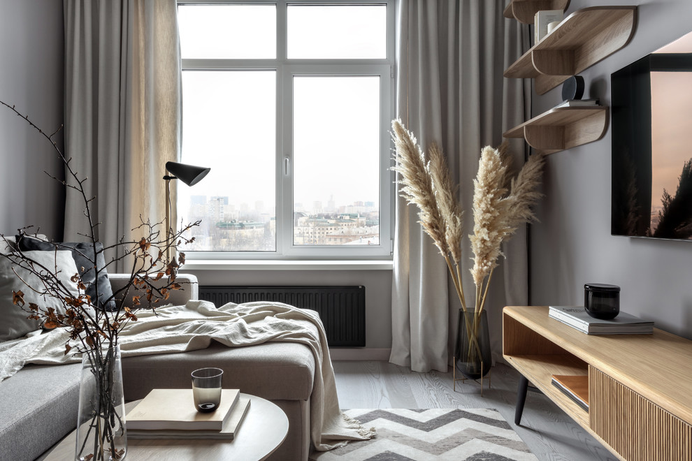 На фото: объединенная гостиная комната среднего размера в скандинавском стиле с серыми стенами, светлым паркетным полом, телевизором на стене и серым полом