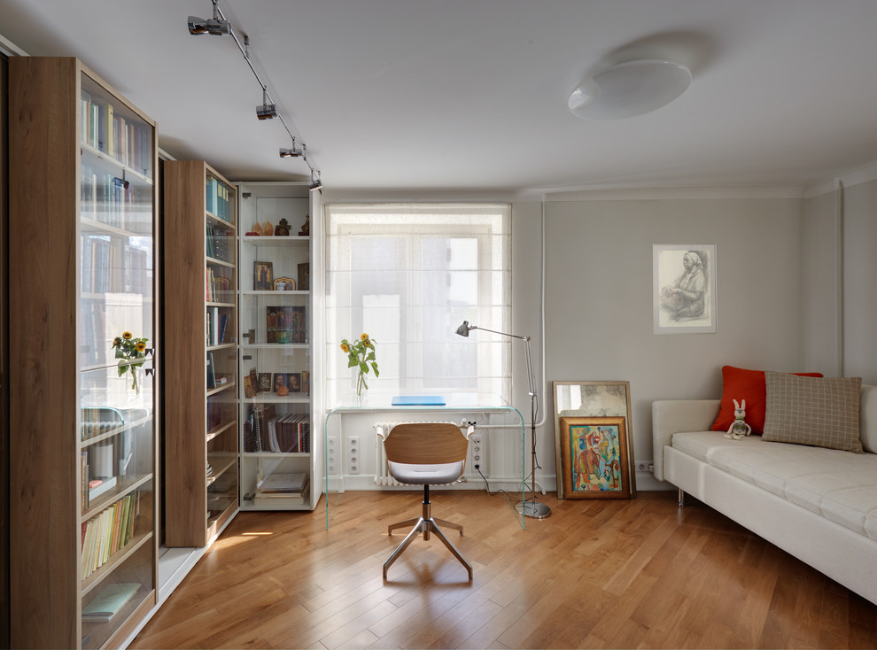 Immagine di un soggiorno di medie dimensioni e aperto con libreria, pareti bianche e pavimento in legno massello medio