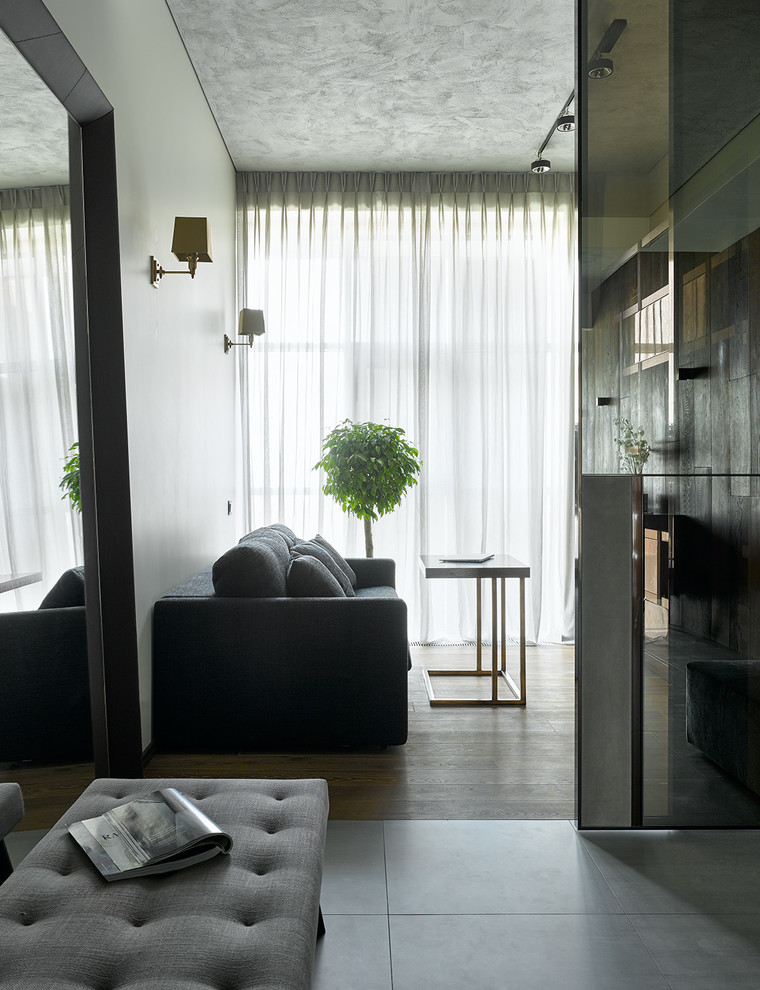 Пример оригинального дизайна: открытая гостиная комната в современном стиле с с книжными шкафами и полками, белыми стенами, темным паркетным полом и коричневым полом