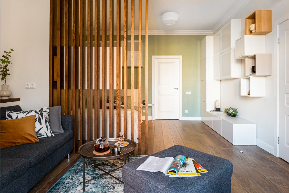 Esempio di un piccolo soggiorno design aperto con libreria, pareti beige, pavimento in laminato e pavimento marrone