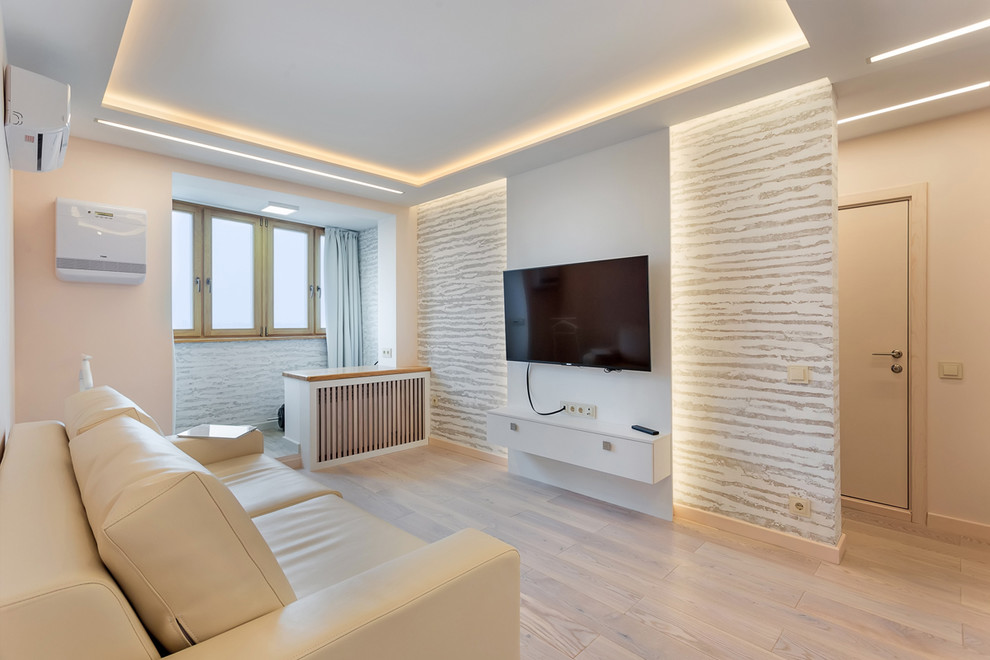Ejemplo de salón para visitas cerrado actual pequeño con paredes blancas, suelo de madera clara, televisor colgado en la pared y suelo blanco