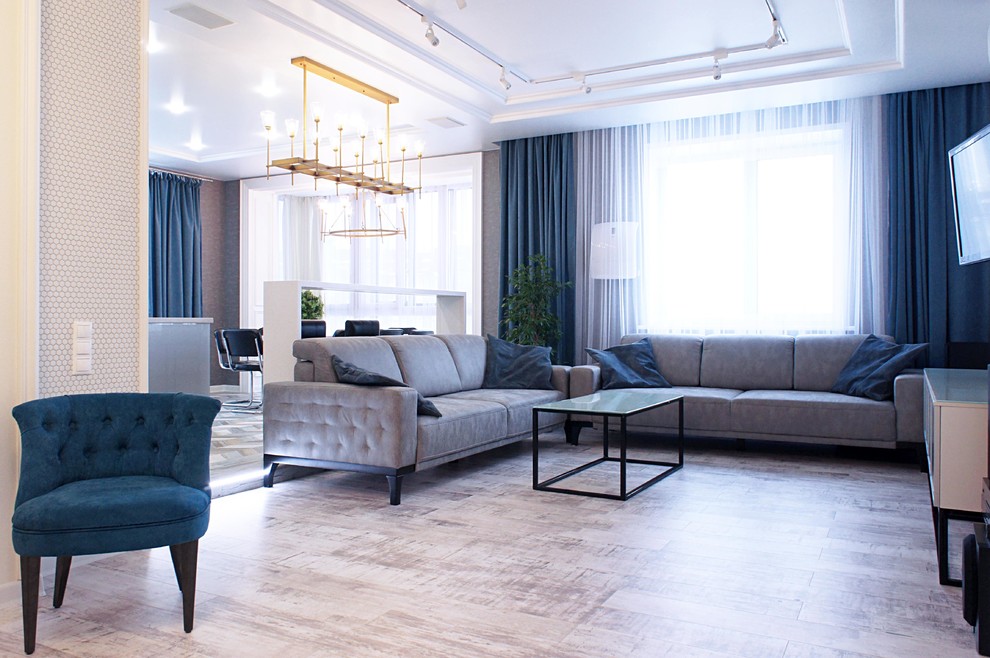 На фото: большая открытая гостиная комната в стиле неоклассика (современная классика) с серыми стенами и полом из ламината с