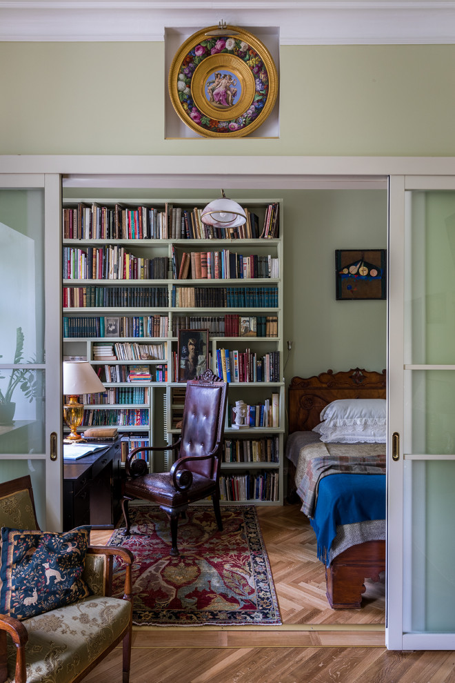 Ejemplo de sala de estar con biblioteca cerrada clásica pequeña con paredes verdes y suelo de madera clara