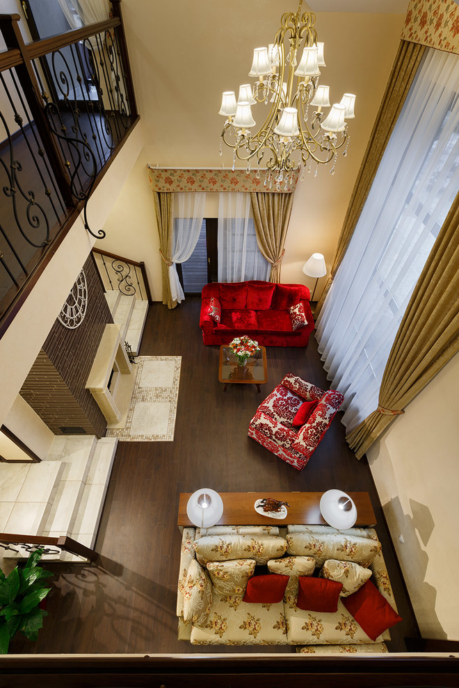 Стильный дизайн: большая парадная, открытая гостиная комната в классическом стиле с бежевыми стенами, полом из ламината, стандартным камином, фасадом камина из плитки, телевизором на стене и коричневым полом - последний тренд