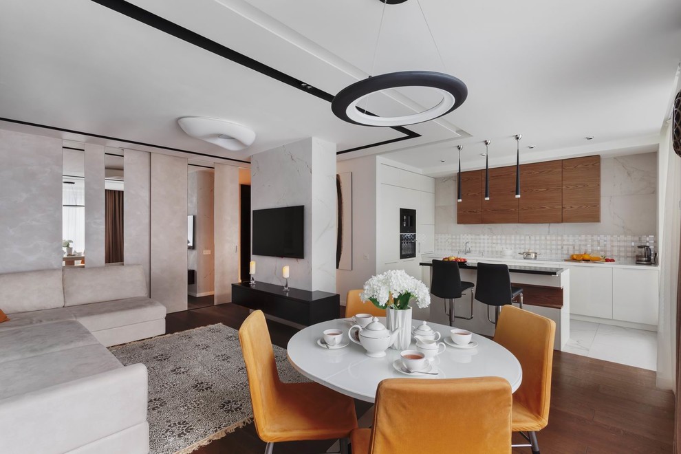 Стильный дизайн: открытая, объединенная гостиная комната среднего размера в современном стиле с белыми стенами, паркетным полом среднего тона, телевизором на стене и коричневым полом - последний тренд