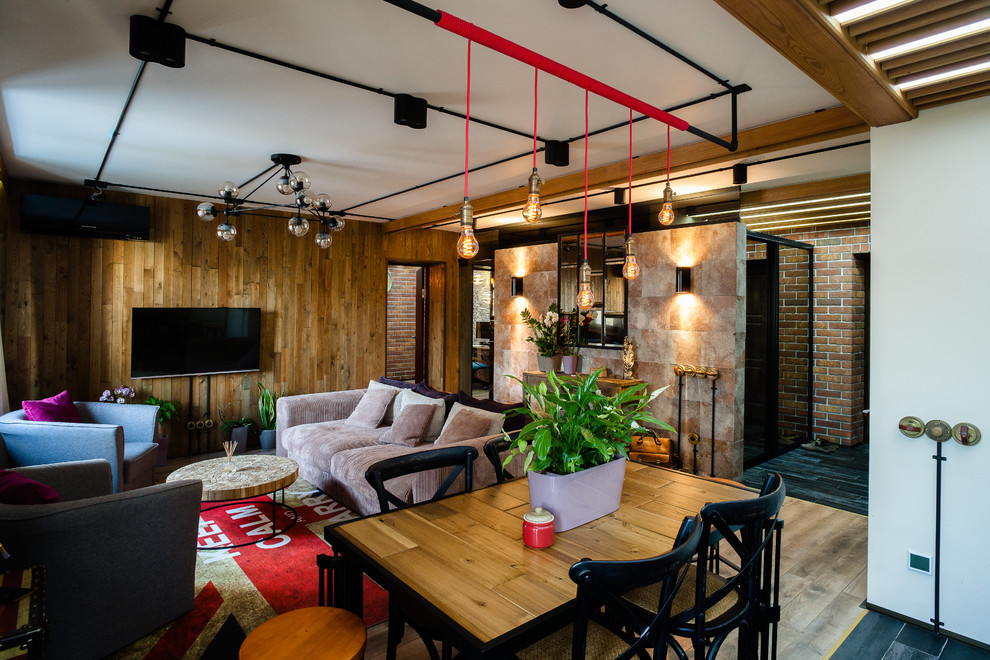 Esempio di un soggiorno industriale di medie dimensioni e stile loft con angolo bar, pareti multicolore, pavimento in legno massello medio, nessun camino e TV a parete
