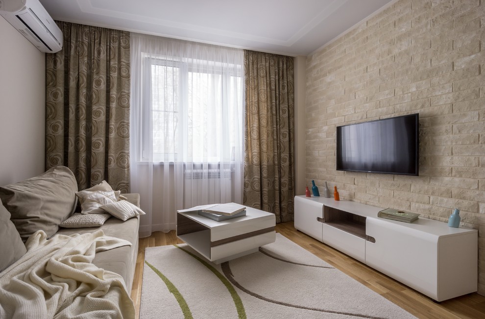 Immagine di un soggiorno design di medie dimensioni e chiuso con pareti beige, pavimento in legno massello medio, TV a parete e pavimento beige