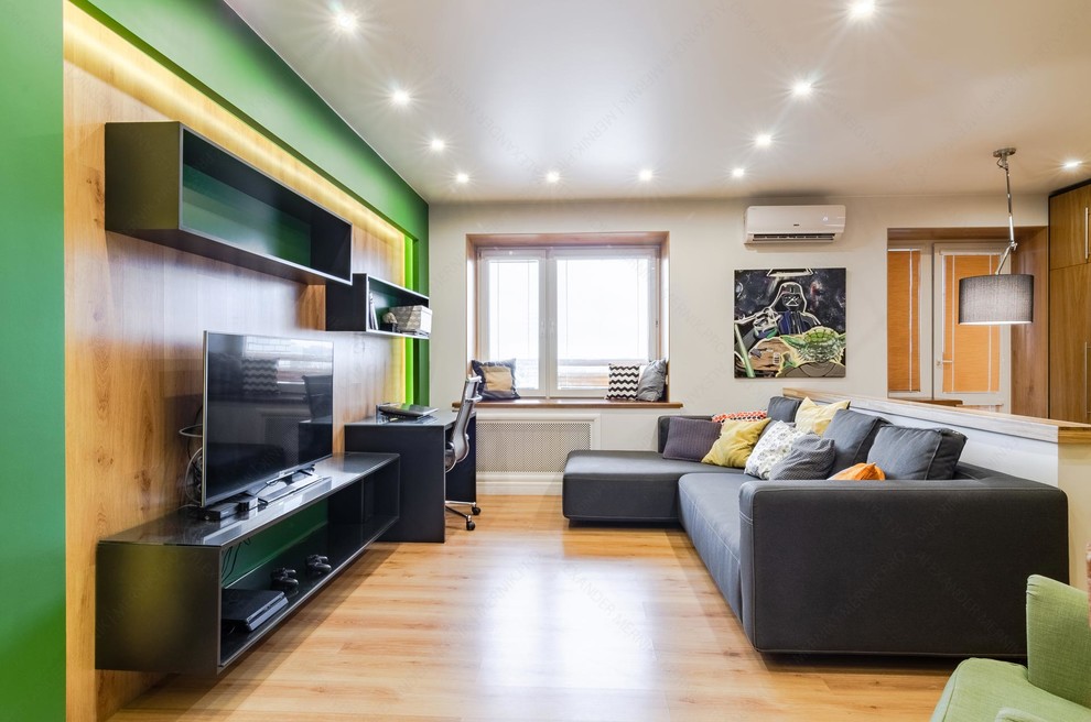 Mittelgroßes Industrial Wohnzimmer ohne Kamin, im Loft-Stil mit grüner Wandfarbe, Laminat, freistehendem TV und braunem Boden in Sonstige