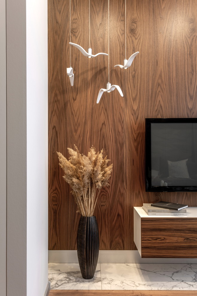 На фото: открытая гостиная комната среднего размера в современном стиле с серыми стенами, полом из ламината, телевизором на стене и коричневым полом без камина с