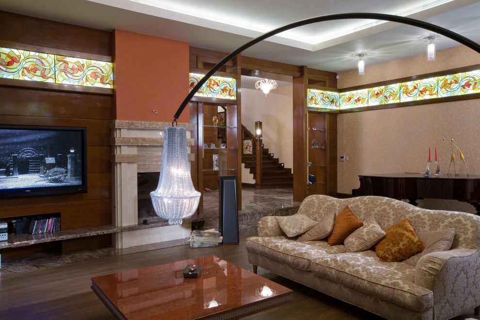 Идея дизайна: изолированная гостиная комната в стиле фьюжн с оранжевыми стенами, паркетным полом среднего тона, стандартным камином, фасадом камина из камня и телевизором на стене