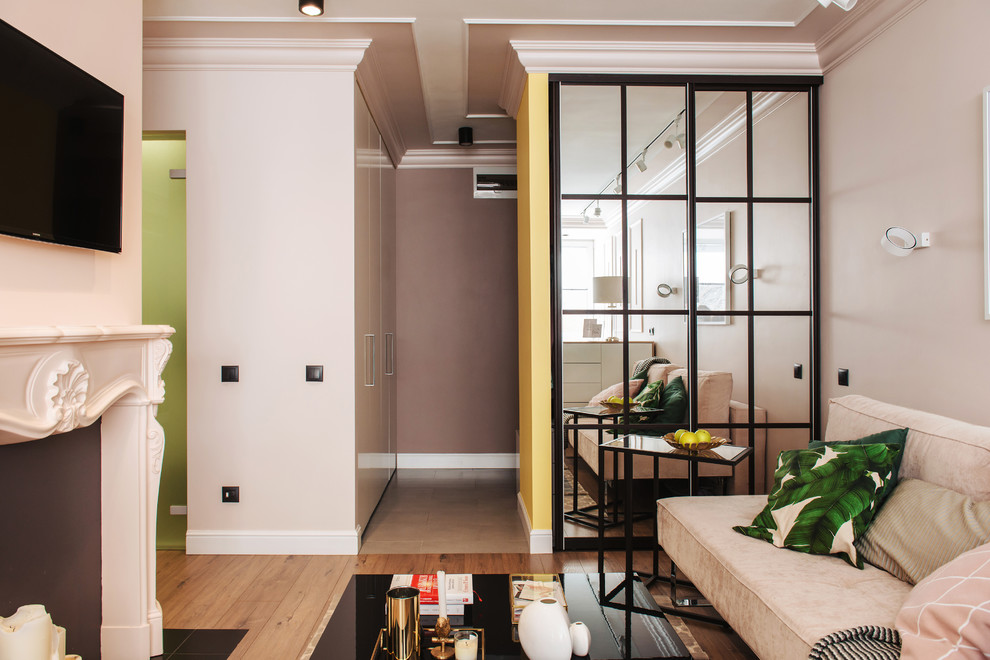 Идея дизайна: открытая гостиная комната в стиле неоклассика (современная классика) с розовыми стенами, паркетным полом среднего тона, стандартным камином и телевизором на стене