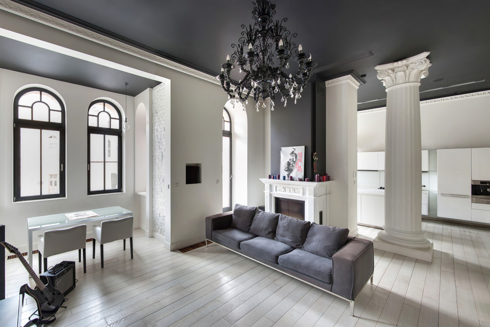 Cette image montre un salon design avec un mur blanc, parquet clair, une cheminée standard et un sol beige.