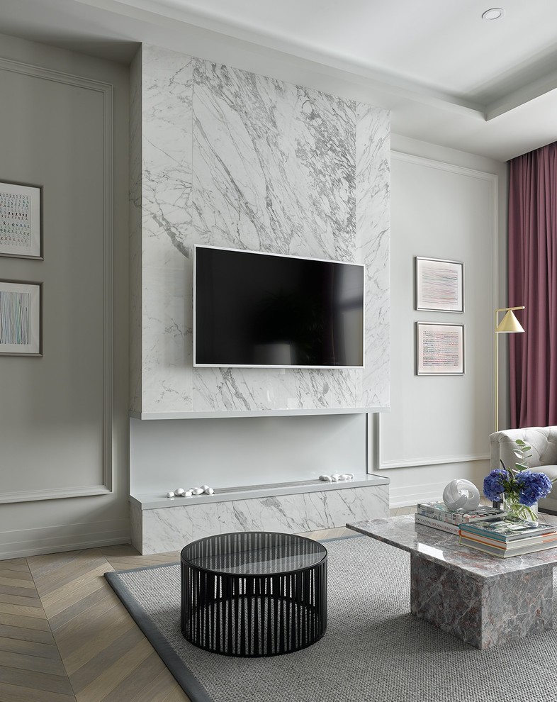 Exempel på ett klassiskt vardagsrum, med ett finrum, grå väggar, ljust trägolv, en bred öppen spis, en spiselkrans i sten, en väggmonterad TV och beiget golv