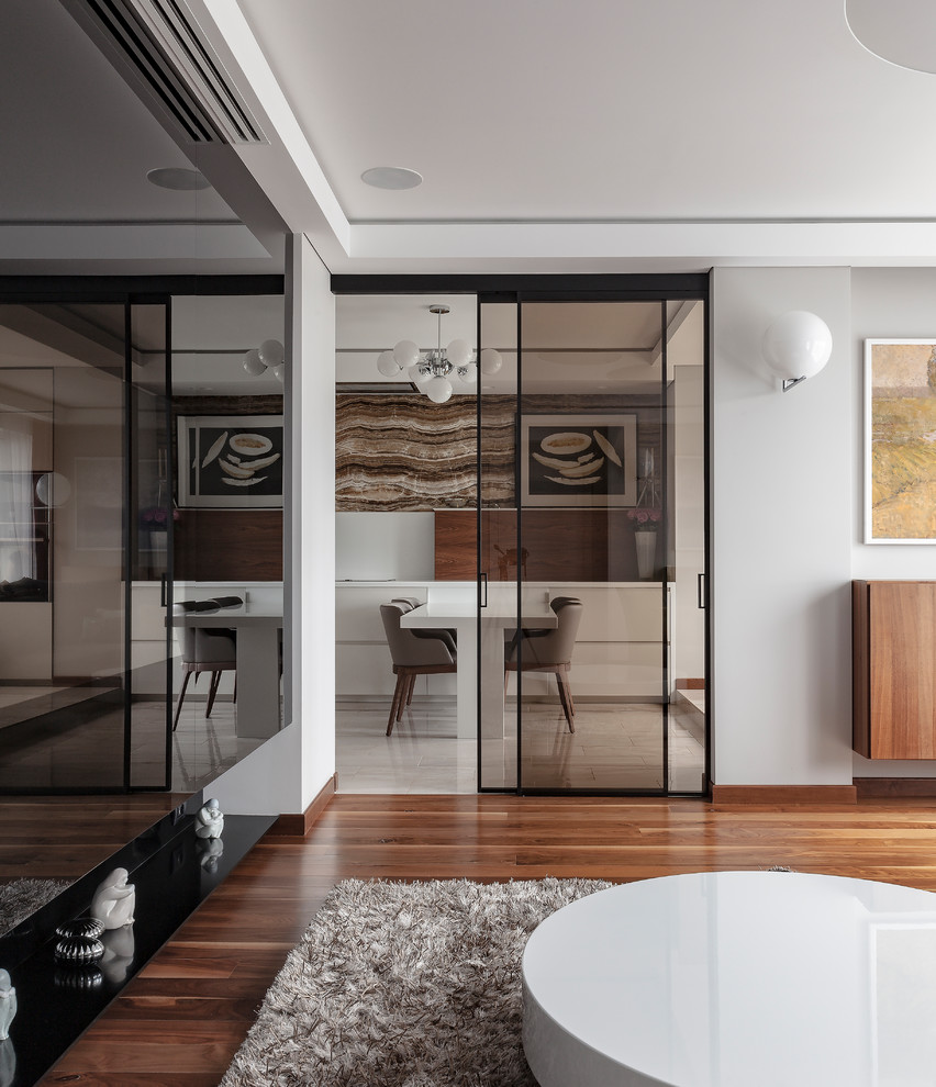 На фото: изолированная, объединенная гостиная комната среднего размера в современном стиле с серыми стенами, темным паркетным полом, скрытым телевизором и коричневым полом с