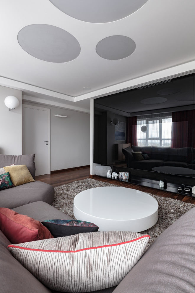 На фото: изолированная гостиная комната среднего размера в современном стиле с серыми стенами, темным паркетным полом, скрытым телевизором и коричневым полом с