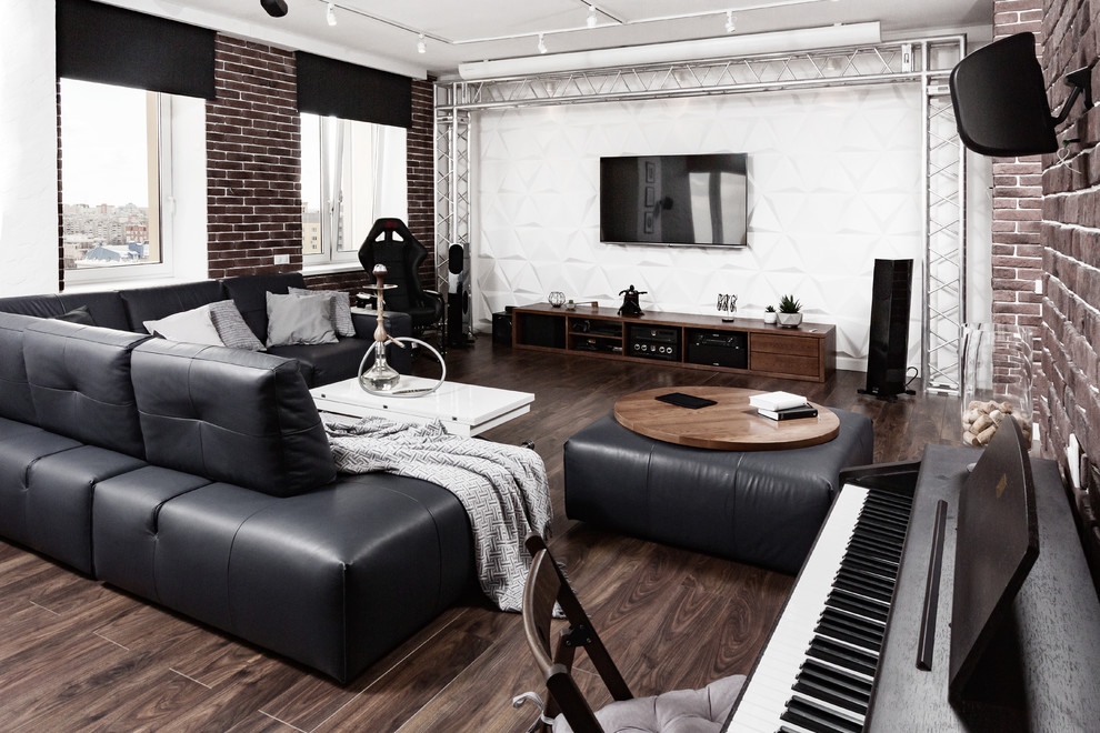 Cette photo montre une salle de séjour industrielle ouverte avec une salle de musique, un mur blanc, parquet foncé, un téléviseur fixé au mur, un sol marron et éclairage.