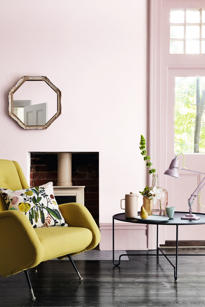 Diseño de salón moderno con paredes rosas, suelo de madera oscura, estufa de leña y suelo negro