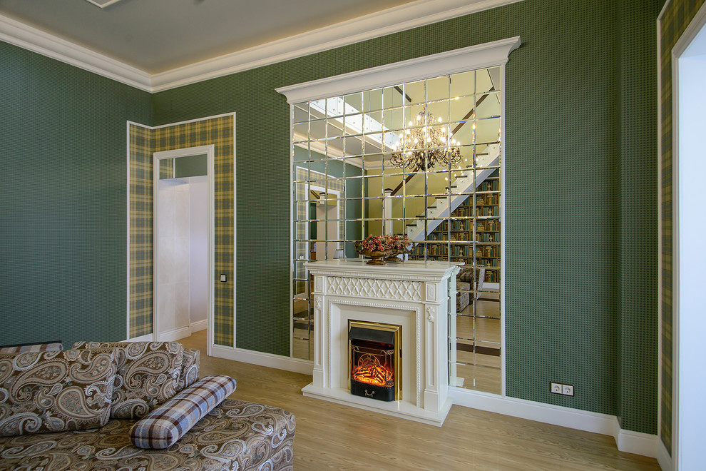 Стильный дизайн: гостиная комната в современном стиле с зелеными стенами, светлым паркетным полом и стандартным камином - последний тренд