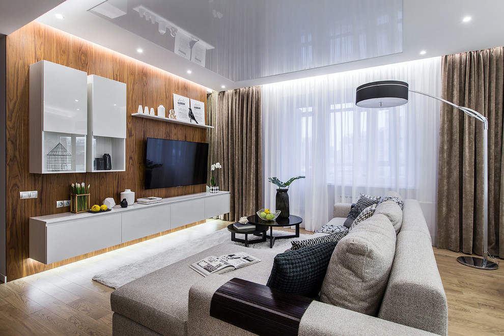 Imagen de salón para visitas abierto actual con paredes marrones, suelo de madera en tonos medios y televisor colgado en la pared