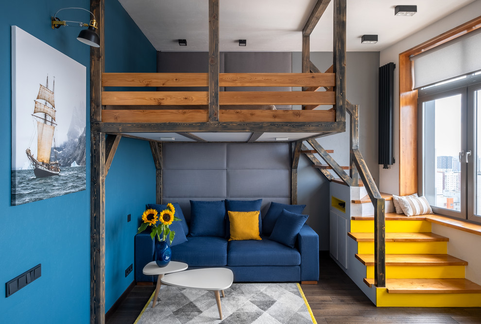 Стильный дизайн: гостиная комната в стиле лофт с синими стенами, темным паркетным полом, коричневым полом и синим диваном - последний тренд