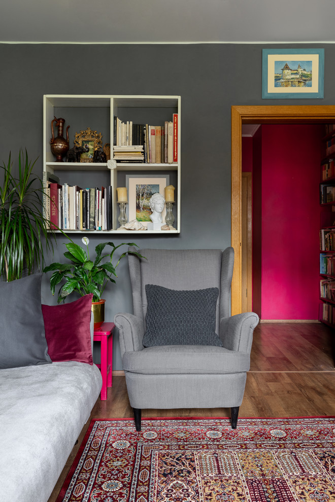 Immagine di un piccolo soggiorno eclettico chiuso con libreria, pareti grigie, pavimento in legno massello medio, nessun camino e TV a parete