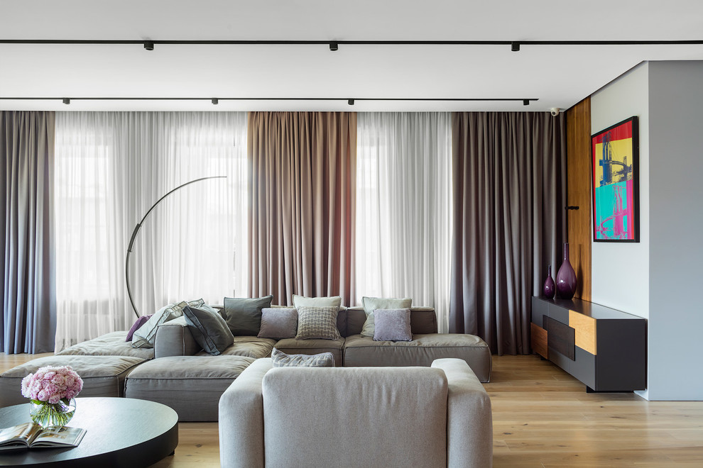 На фото: гостиная комната:: освещение в современном стиле с серыми стенами, светлым паркетным полом и бежевым полом