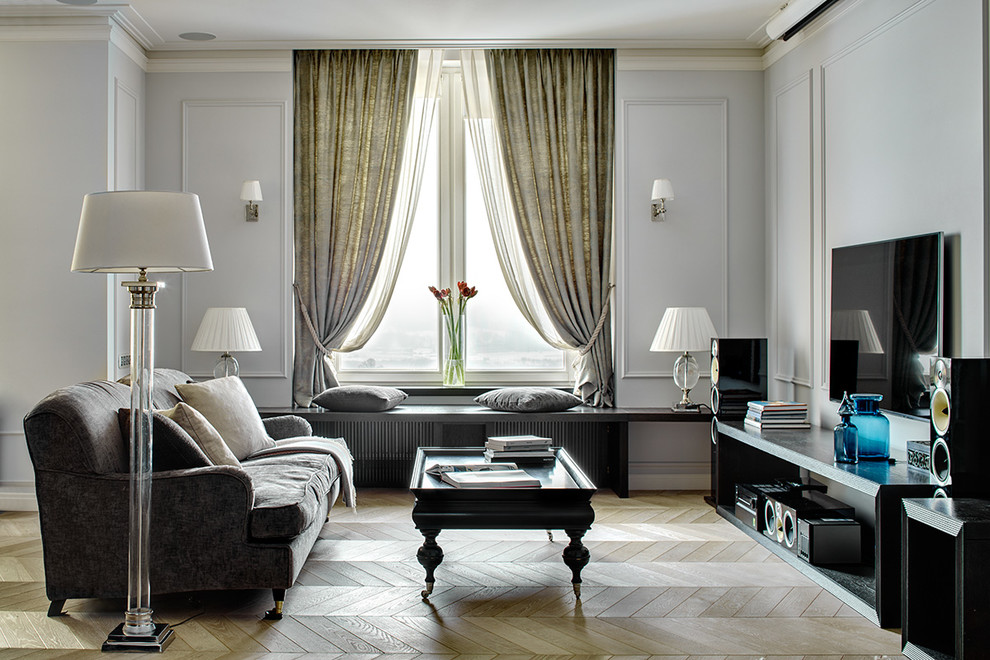 Идея дизайна: открытая гостиная комната среднего размера в стиле неоклассика (современная классика) с серыми стенами, светлым паркетным полом и телевизором на стене без камина