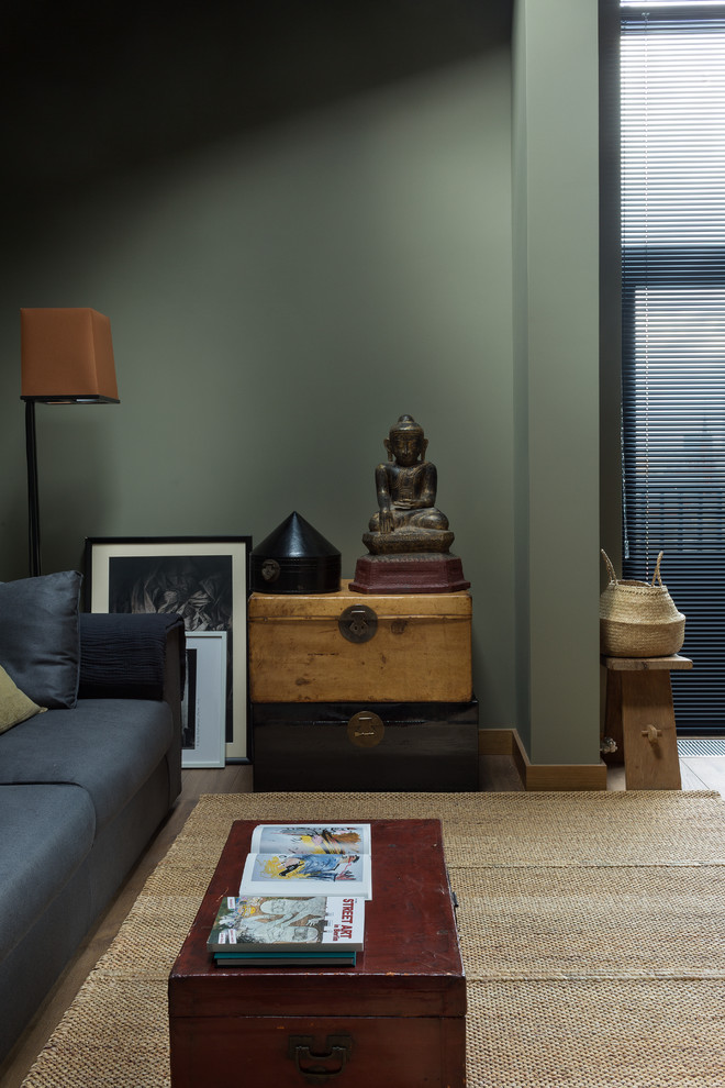 Exemple d'un petit salon mansardé ou avec mezzanine tendance avec un mur vert, un sol en bois brun, une cheminée standard, un manteau de cheminée en pierre et un sol marron.